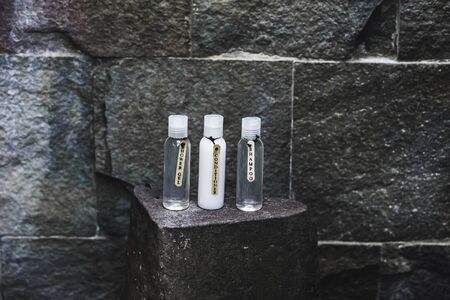 Different bottles with shampoo, gel and conditioner on stone shelf in outdoor shower. Organic cosmetics concept.の写真素材