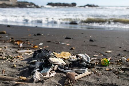 Environmental pollution. Heap of used rubber shoes on the beach in Bali, Indonesia. Social rubbish recycling problemの写真素材