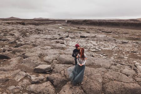 Couple in love walking and kissing in Iceland. Stone volcanic desert around, in the middle of...