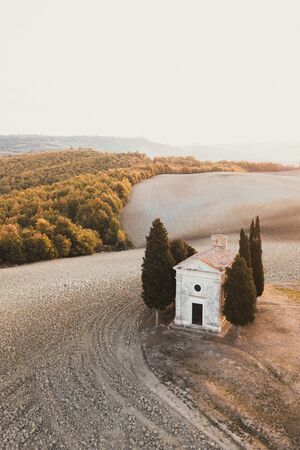 Aerial drone view of Cappella della Madonna di Vitaleta, Tuscany, Italy. Traditional italian architecture. Autumn landscape of Tuscan hills San Quirico DOrcia. Empty agricultural fields in autumn.の写真素材