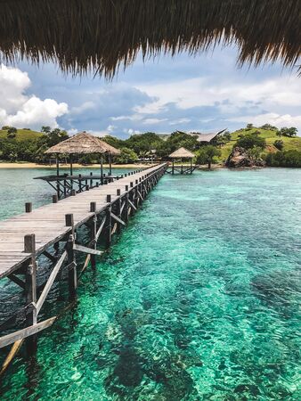 View of tropical island with turquoise transparent clear water from wooden pier. Vacations concept....