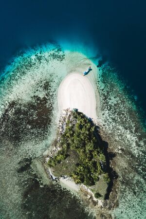 Aerial view of white sand beach on small tropical coral reef island with tourist diving boat. Tropical background and travel concept.の写真素材