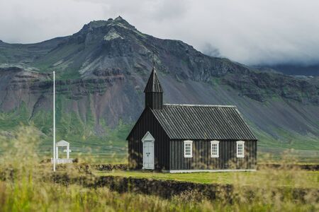 Famous black church of Budir at Snaefellsnes peninsula region in Iceland. Amazing rocks and mountain view on background. Summer in Iceland.の写真素材