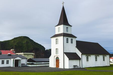 Church with Black roof and white walls in traditional nordic minimalist style on Vestmannaeyjar Heimaey island in Iceland. Simple architecture, green grass, nobody around.の写真素材