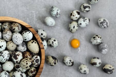 Wooden bowl with heap of small quail eggs on gray concrete background. Easter cooking concept.