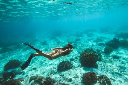 Woman snorkelling underwater with snorkel mask in clear transparent water in beautiful tropical lagoon with coral reef. Freediving activity. Leisure on vacations.の写真素材