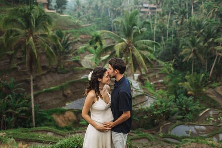 Young latin pregnant woman with husband with amazing view of Ubud rice terraces. Pregnant couple happy together.の写真素材