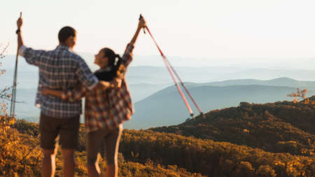 Couple hikers blurred on foreground enjoying amazing autumn mountain view at sunset. Layered horizon...
