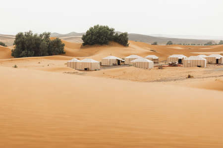 Contemporary luxury glamping camp in Morocco Sahara desert. Sand dunes around. Many white modern eco tents.の写真素材