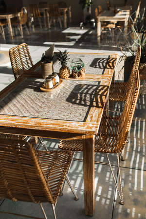 Wicker rattan handmade chairs and wooden table. Trendy furniture design. Summer cafe terrace.の写真素材