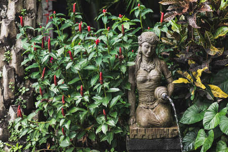 Female stone carved statuette as fountain in balinese traditional garden. Traditional element of architecture design in Bali.の写真素材