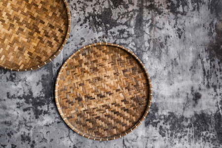 Gray shabby concrete wall decorated with wicker handmade round trays. Eco style and concept, Moroccan culture. Hipster cafe design.の写真素材