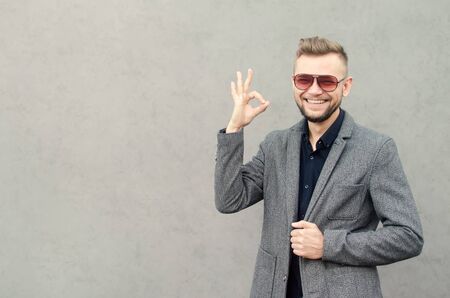 smiling man with a beard in sunglasses and jacket showing ok. place for text