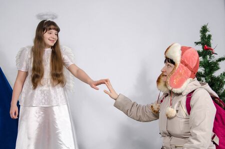 a woman in winter clothes touching the hand of a girl in an angel costumeの写真素材