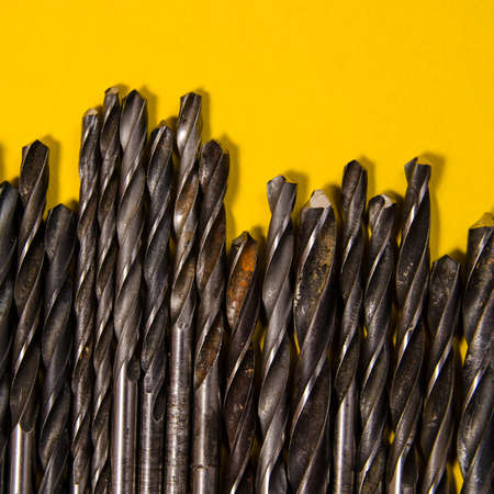 a lot of drills of different sizes on a bright yellow background. square view.の写真素材
