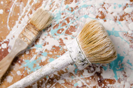 two brushes on a hardboard stained with paint backgroundの写真素材