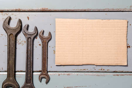 several wrenches and piece of corrugated paper box on the background of metal painted platesの写真素材