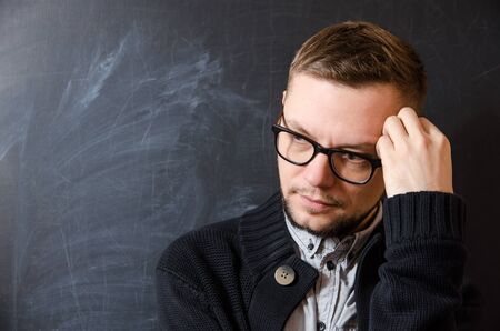 a bearded man with glasses reflecting against the background of school boardの写真素材
