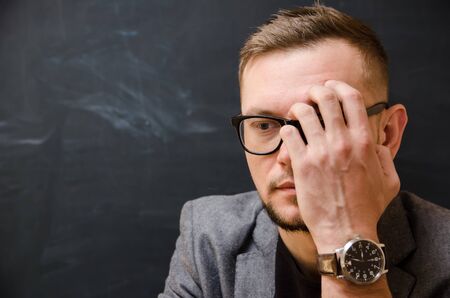 a bearded man in glasses in a pensive pose with a face half-covered with his handの写真素材
