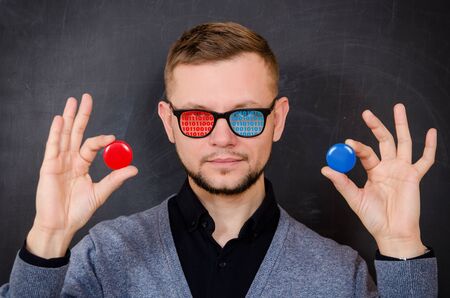 a man with glasses with a binary code on the glass offers to choose one of the options for virtuality - choosing a red or blue chipの写真素材