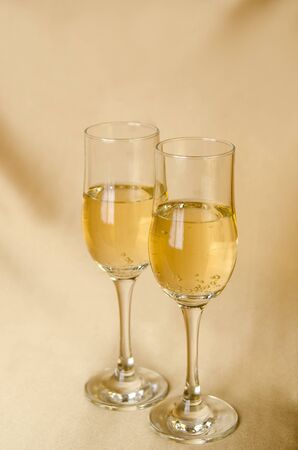 two glasses of champagne on a background of a fabric of golden color. vertical view.の写真素材