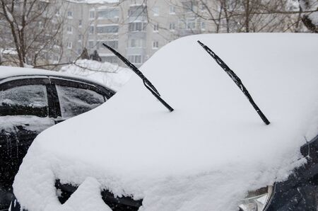 snow-covered car with windscreen wiper during winter snowの写真素材
