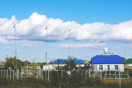 meteorological station with house on a background of blue sky with white cloudsの写真素材