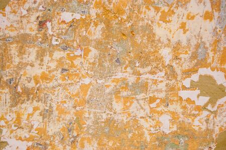 peeling paint wall painted with ocher, grey and orange colors.