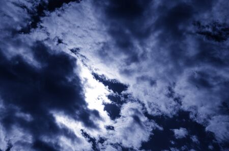 dark blue sky with a stratocumulus clouds and the sun behind them. toned.の写真素材