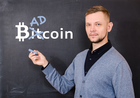 Man near a black school board on which is written bitkoin,  part of the word Bitcoin is replaced by Bad. The concept of unreliability and instability of bitcoin. The concept of the bitcoin collapse.の写真素材