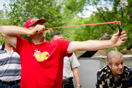 KOMSOMOLSK-ON-AMUR, RUSSIA, AUGUST 1, 2015. Public open Railroader's day. man in red shoots from a slingshot at competitionsのeditorial素材