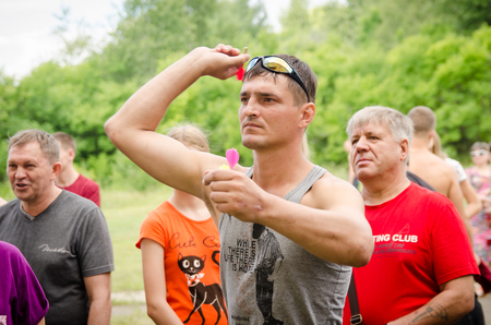 KOMSOMOLSK-ON-AMUR, RUSSIA, AUGUST 1, 2015. Public open Railroader's day. man preparing to throw a dart at a target in amateur competitionsのeditorial素材