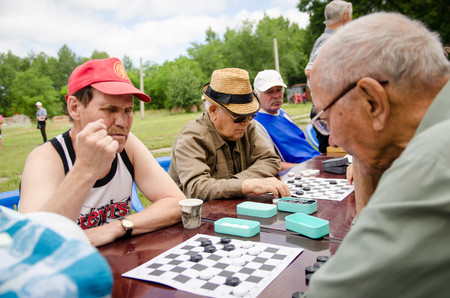 KOMSOMOLSK-ON-AMUR, RUSSIA, AUGUST 1, 2015. Public open Railroader's day. elderly people play checkers in the park. amateur competitions.のeditorial素材