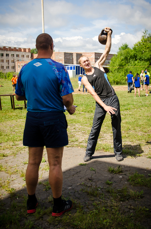 KOMSOMOLSK-ON-AMUR, RUSSIA, AUGUST 1, 2015. Public open Railroader's day. judge is looking at man raises a weight in an amateur competitionのeditorial素材