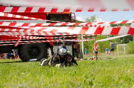 Komsomolsk-on-Amur, Russia - August 8, 2016. Public open Railroader's day. girl in the form of a fireman crawl across the obstacle courseのeditorial素材