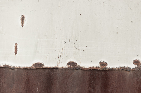 brown rusty metal sheet partially painted with light paint. grunge background with space for text or...
