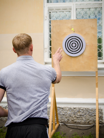 Komsomolsk-on-Amur, Russia - August 1, 2016. Public open Railroader's day. man throws dart at target in amateur competitionsのeditorial素材