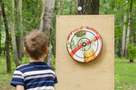 Komsomolsk-on-Amur, Russia - August 19, 2018. little boy throws dart at target with a picture of burning cigarettes. visual healthy lifestyle.のeditorial素材