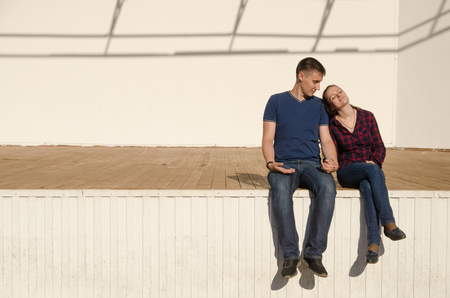 couple guy and girl are sitting next on the open stage under the bright rays of the summer sun. close view.の写真素材