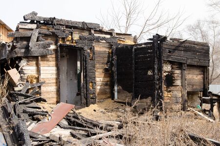 Brown and black burnt house of wooden planks with embossed texture without door and broken wall. 
damage to the building from fire without the possibility of its restoration. concept of loss of real estate or home. property insurance.の写真素材