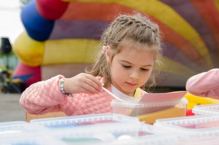 Komsomolsk-on-Amur, RUSSIA - SEPTEMBER 2, 2019. girl with pigtails draws a picture with colored sand. child creative development conceptのeditorial素材
