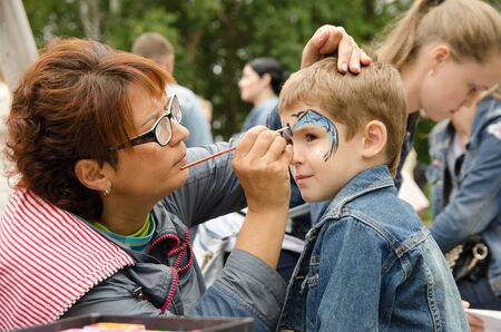 Komsomolsk-on-Amur, RUSSIA - SEPTEMBER 2, 2019. female artist paints a bat mask on a boyâ€™s...