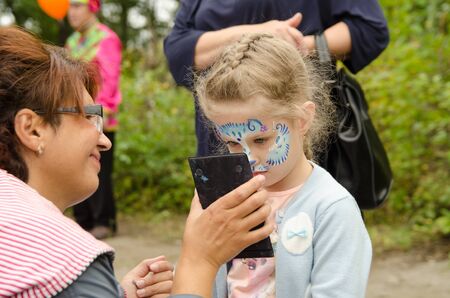 Komsomolsk-on-Amur, RUSSIA - SEPTEMBER 2, 2019. girl with a painted animal mask on her face looks at...
