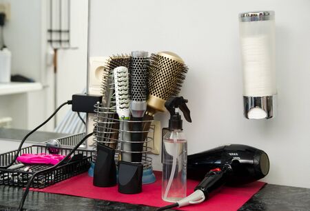 various professional hair brushes and a black hairdryer on a table in a hairdressing salon.の写真素材