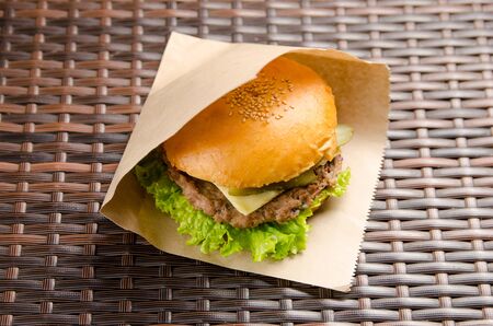 Cheeseburger with cutlet, cheese and lettuce in a paper bag. fast food takeaway.の写真素材