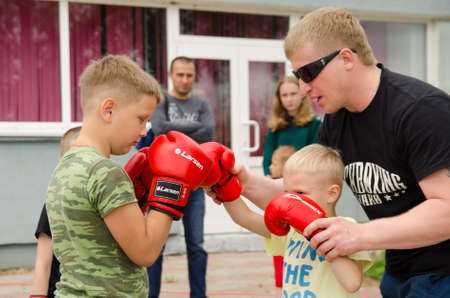 Komsomolsk-on-Amur, RUSSIA - JULY 21, 2018. Kickboxing coach shows the boy how to make punch in sparring. Training outdoor in summerのeditorial素材