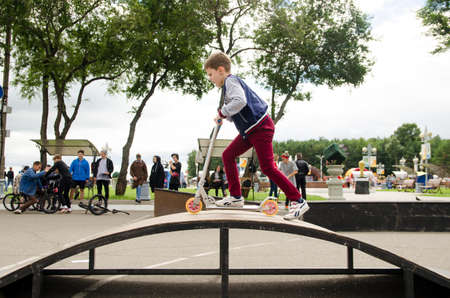 Komsomolsk-on-Amur, RUSSIA - JULY 21, 2018. Boy on a stunt scooter on top of an iron slideのeditorial素材