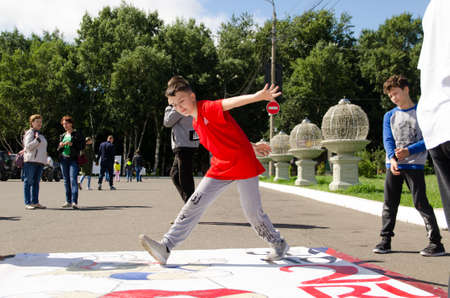 Komsomolsk-on-Amur, RUSSIA - JULY 21, 2018. Boy dances breakdance on the street in front spectators. hip hop dancerのeditorial素材