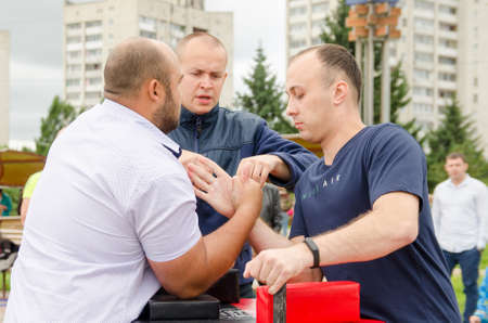 Komsomolsk-on-Amur, RUSSIA - JULY 21, 2018. the judge sets the wrestlers' hands correctly before the start of the bout. Arm wrestling competitions.のeditorial素材