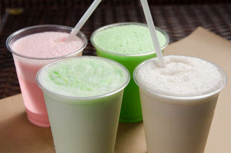 white, pink and green milkshakes in transparent cups with a straw.
